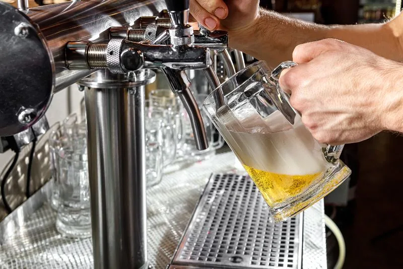 Drunk driving image - bartender pours draft beer into a large mug that's half full.