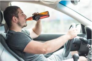 Michigan man in his 30s leans back in driver's seat as he chugs a bottle of beer.