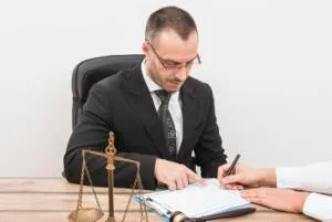 Personal injury attorney reviews settlement offer at a desk as client points to document with pen.