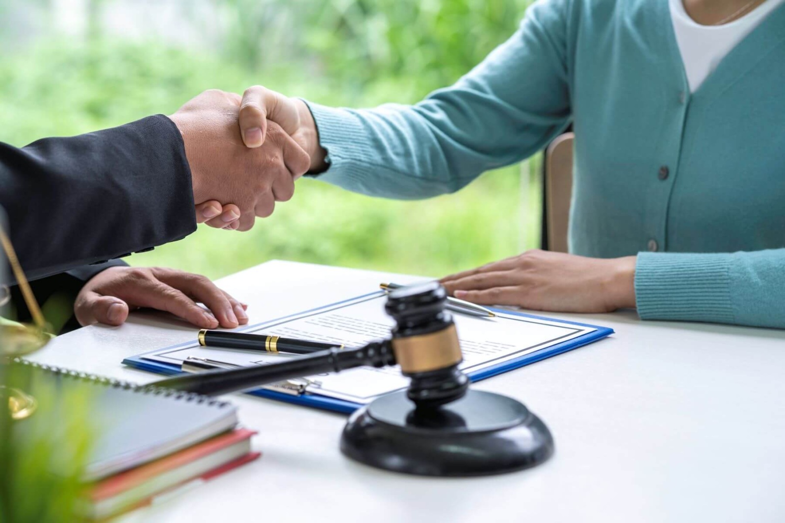 Close-up of attorney and client shaking hands during personal injury settlement.