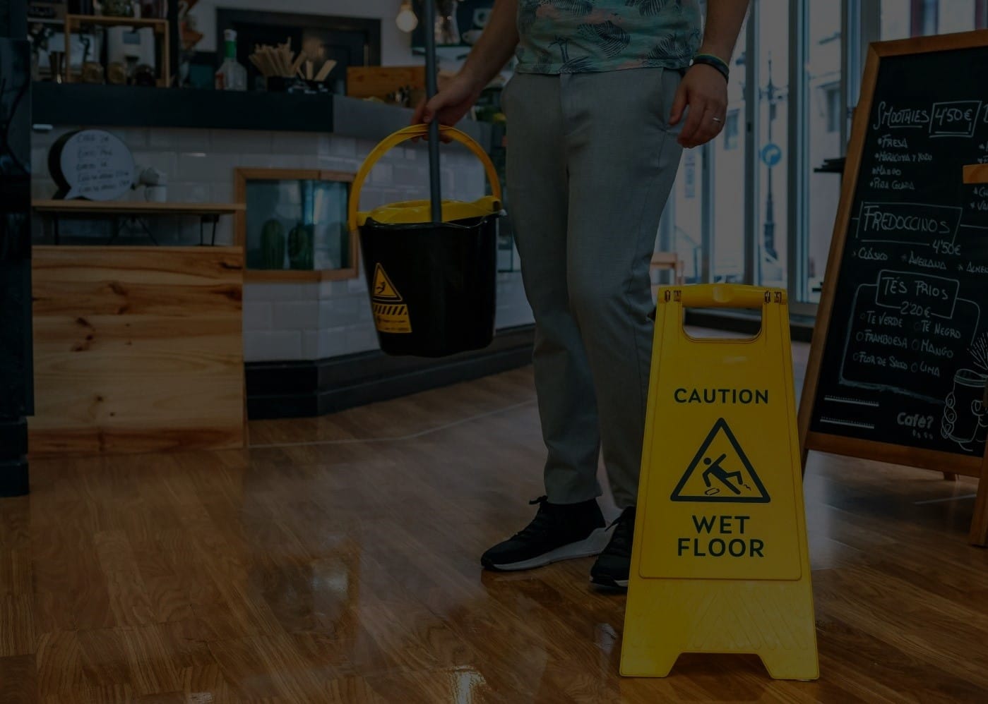image of worker with mop bucket and wet floor signs