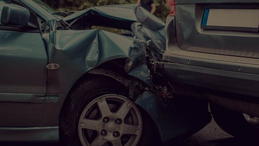 Closeup of an SUV and sedan with a crumpled hood involved in a rear-end collision.