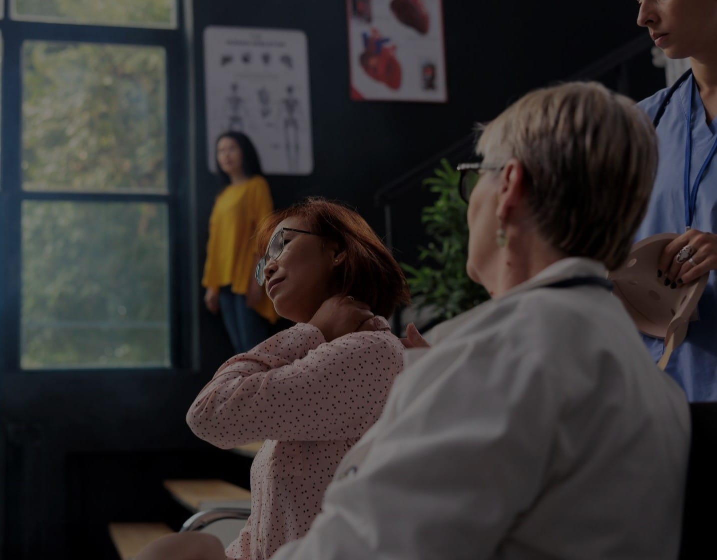 Asian woman in Grand Haven grips neck after healthcare workers help her remove cervical brace.