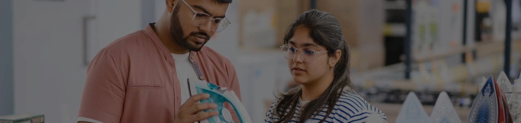 Indian couple checks steam iron for product defects while shopping in an appliance store.