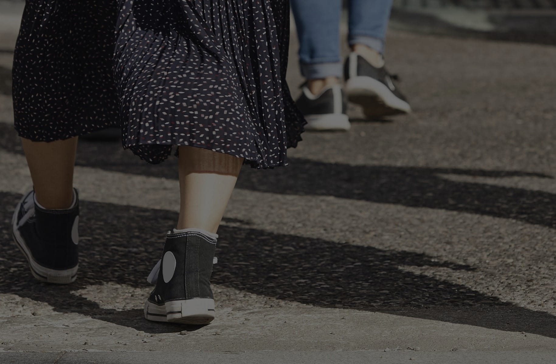 Closeup of pedestrians’ legs and feet as they cross the street.