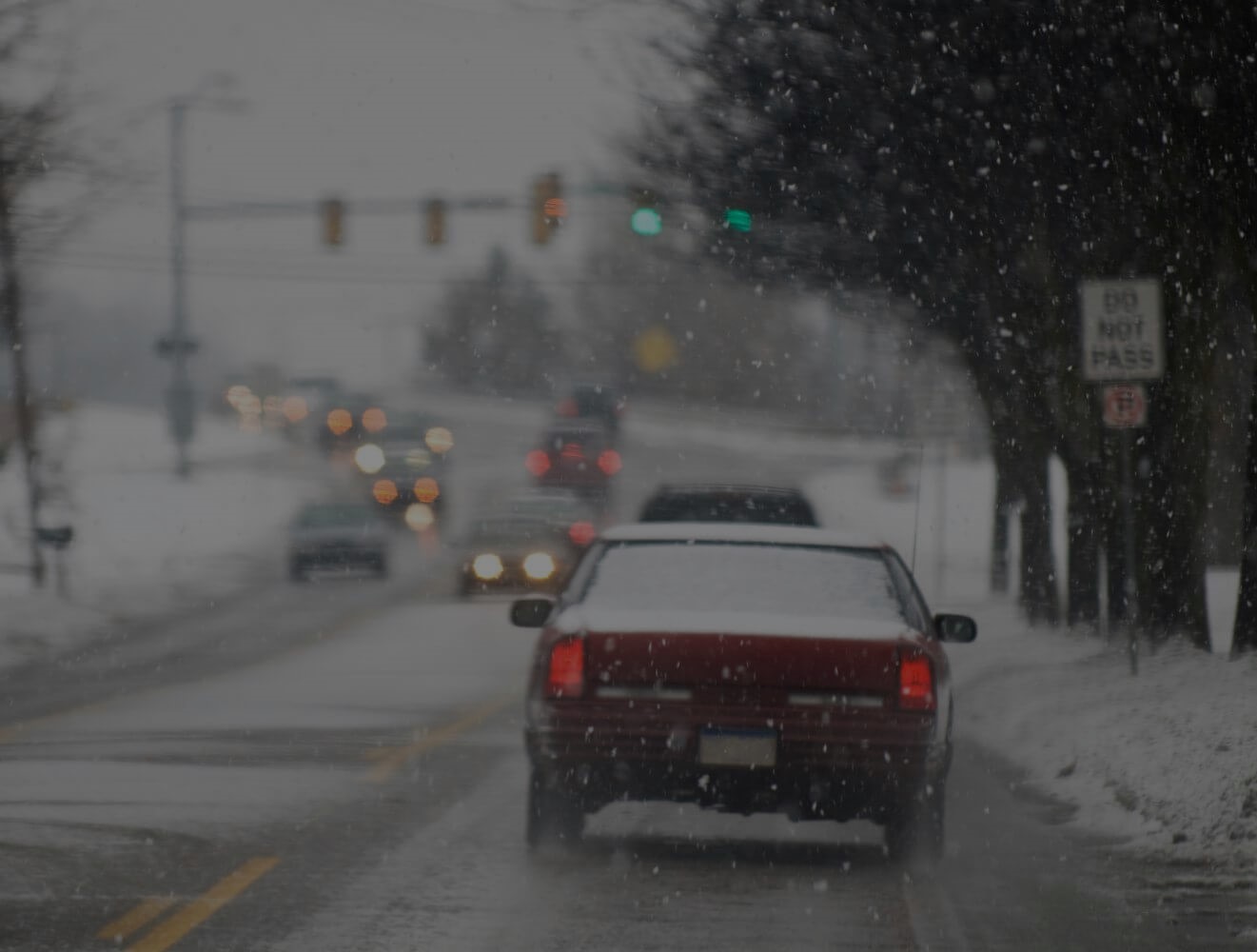 Cars drive through a busy intersection near Holland in snowy conditions.