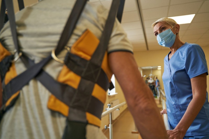 Michigan man undergoes physical therapy in overhead harness to prove pain and suffering damages.