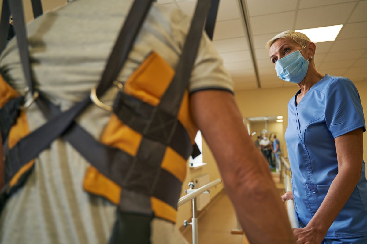 Michigan man undergoes physical therapy in overhead harness to prove pain and suffering damages.