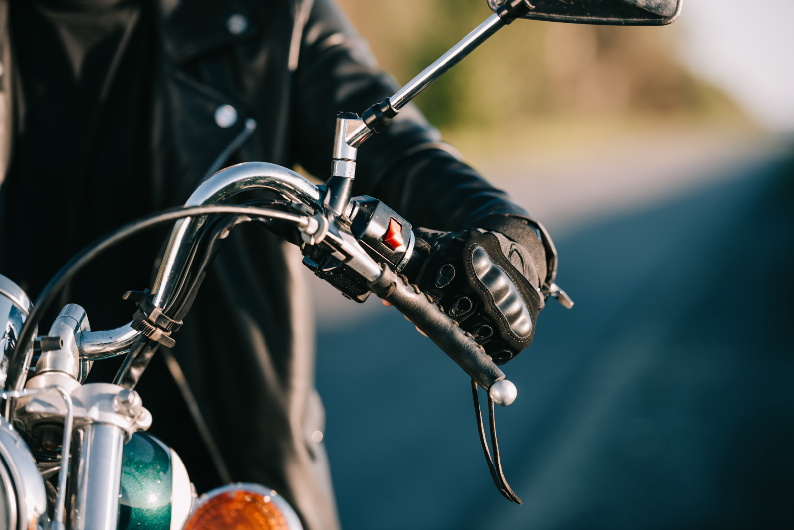 a motorcycle rider cropped half out of the frame on the left, and behind him is an out-of-focus road.